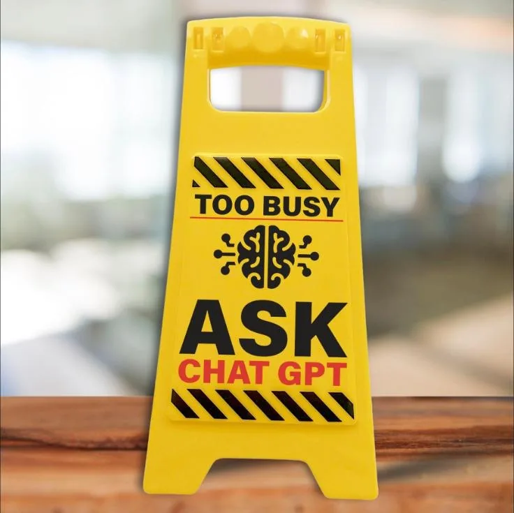 Yellow desk warning sign reading Too busy, ask Chat GPT