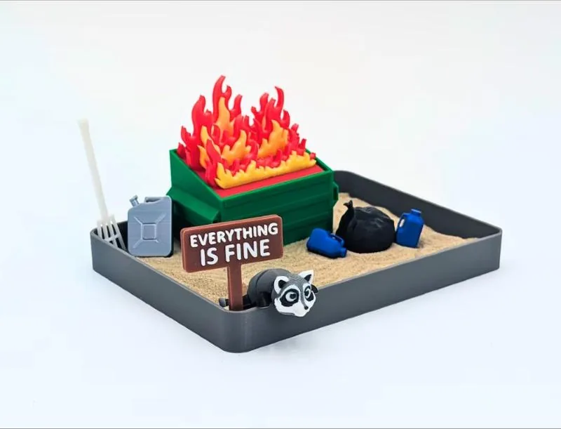 Miniature sand garden with a tiny burning dumpster and a rake