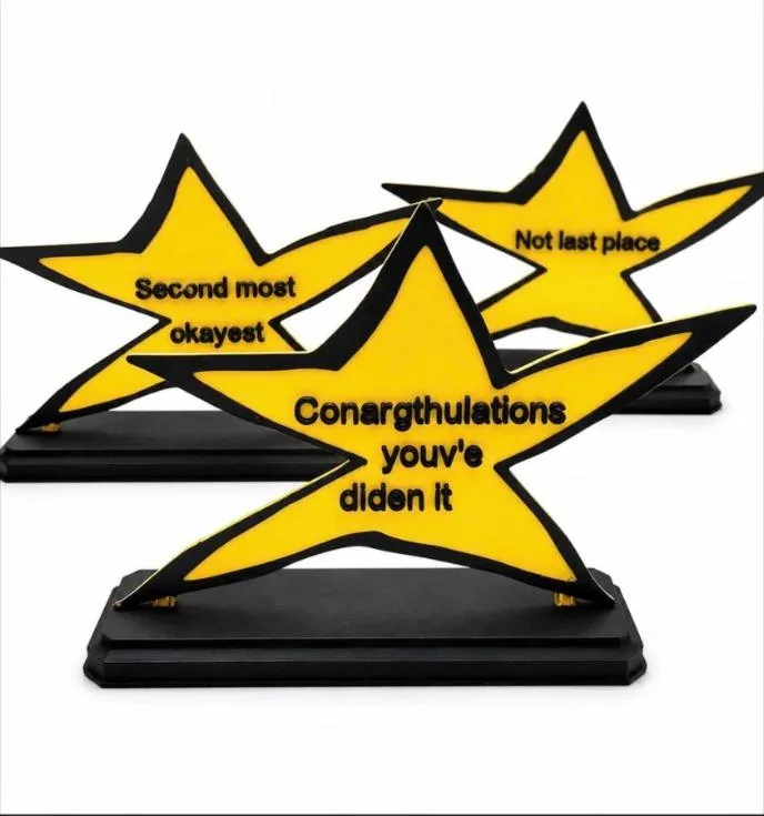 Yellow 3D-printed star trophies on black bases with joke messages