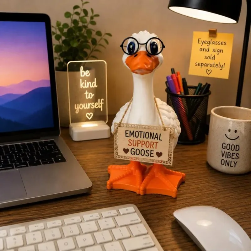 The Emotional Support Goose on a desk, glasses on, sign around its neck